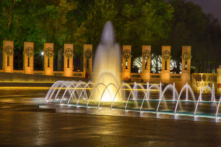 The fountains and pillars of the Waorld War Two memorial in Washington, DC are aglow on a summer night.のeditorial素材