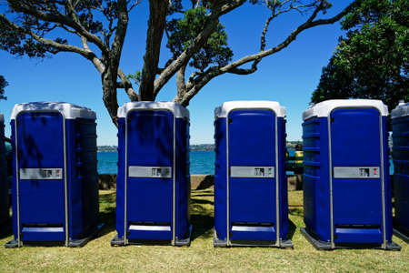 A row of outdoor four blue toilet cubicles at an event.の写真素材