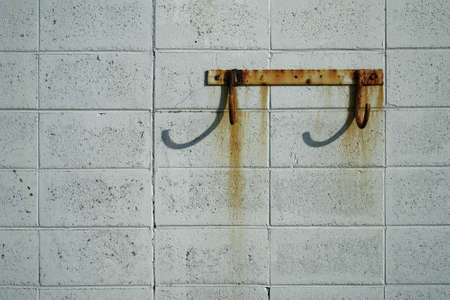 Rusty hooks on a rust stained breeze block wall at the sea front.の写真素材