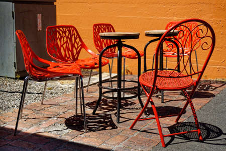 Bright red chairs, stackable and collapsible, and wooden tables in a cafe garden, New Zealand.の写真素材