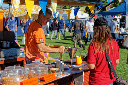 Mapua, Tasman/New Zealand â April 17 12, 2017: [Girl buying mini pancakes at a Dutch food stall, at an open air market in New Zealand.]のeditorial素材