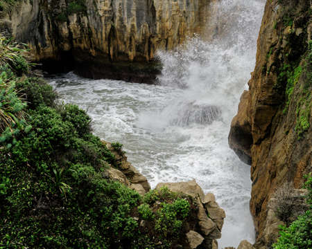 Wave crashing in the surge pool at The Pancake Rocks at Dolomite Point, geological formation and tourist destination must see at Punakaiki, Greymouth, West Coast, South Island, New Zealand.の写真素材