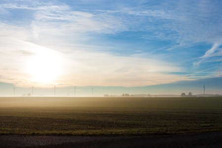 Foggy winter morning on the fields, with wind turbines in the background の写真素材