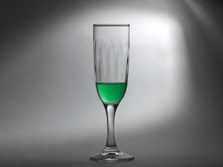 Transparent green liquid in a glass cup on abstract grey background の写真素材