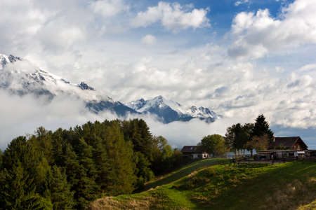 Small farm in the Alps with snowcapped mountains in the background の写真素材
