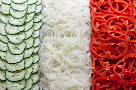 Different colorful vegetables (cucumber, onion, paprika) grouped like the italian flag.の写真素材