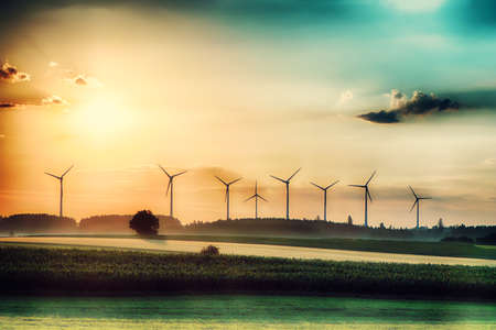 Surreal morning sunrise on the fields with wind turbines in the background.