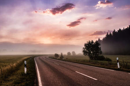 Empty road at morning sunrise leading into the mist. Concept of beginning, hope and freedom.の写真素材
