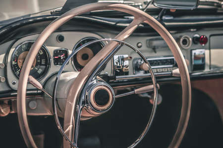 Close-up, detailed photo of the interior, dashboard, steering wheel and speedometer of a classic oldtimer luxury sports car.の写真素材