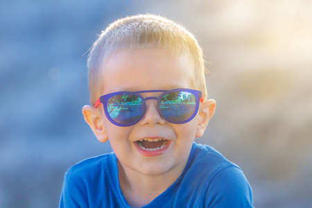 Young white preschool 4 years old boy in sunglasses happily laughing while looking at the camera on...