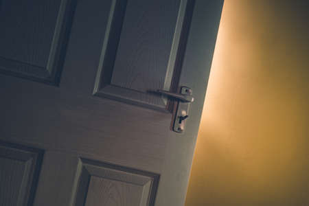 Light shining through open door in dark room with yellow wall. Mystery, success, hope concept.の写真素材