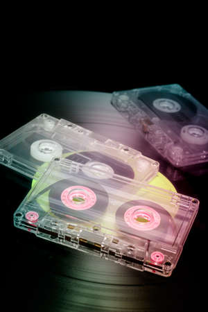 Old vintage audio cassettes on a vinyl record. Retro music formats of the eighties. Colorful analog hifi concept.の写真素材