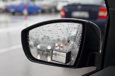 Wet by the rain the car mirror, blurry cars in mirror. Blurred cars in the parking lot in the background.の写真素材