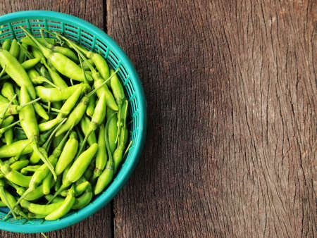 Green chili in the basket on the wooden planksの写真素材
