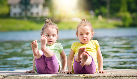 Twing girls are exercising on a lake shoreの写真素材