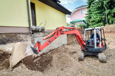 A big family house is being rebuilt with the help of an excavatorの写真素材