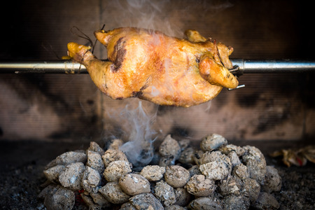 Cooking rotisserie chicken on the grill with Charcoal and Briquettes in the professional steak house or barbecue restaurantの写真素材
