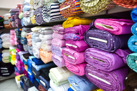 Rolls of fabric and textiles in a factory shop. Multi different colors and patterns on the market.