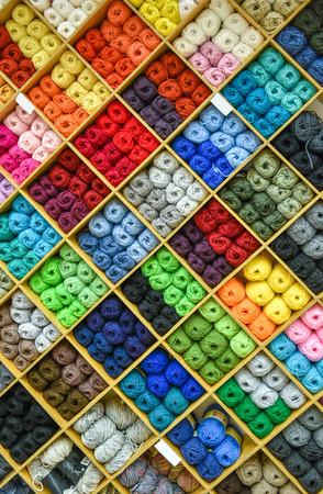 Yarns or balls and of wool are forming lovely colorful pattern. Accessories for haberdashery in a Fabric store shelves. Multi colored picture.の写真素材