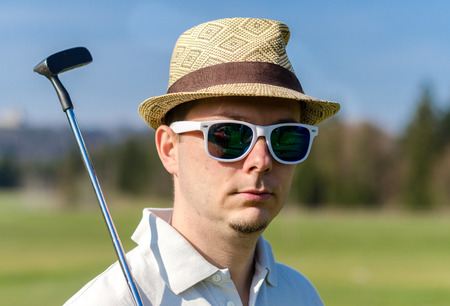 Portrait of a golfer man with a hat and sunglases.