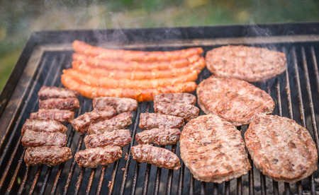 Grilling Meat on barbecue grill with coal. Cevapcici, burgers and sausages on charcoal barbecue BBQ in the natureの写真素材