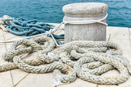 Old Stone Mooring on a stone paved pier with sea in the backgroundの写真素材