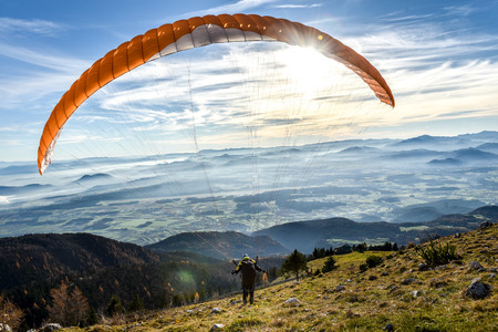 Paraglider is starting. Parachute is filling with air in the mountains alps ona sunny day.の写真素材