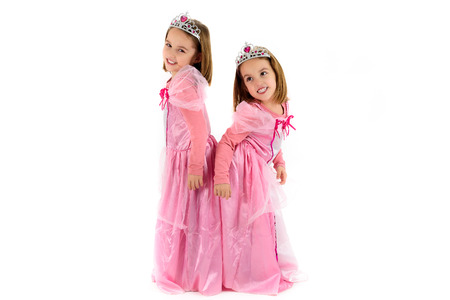 Portrait of Little Twin Girls dressed as princess in pink. Happy children ready for costume party. Cute smiling joyful twins are wearing royalty costume of princess or queen.の写真素材