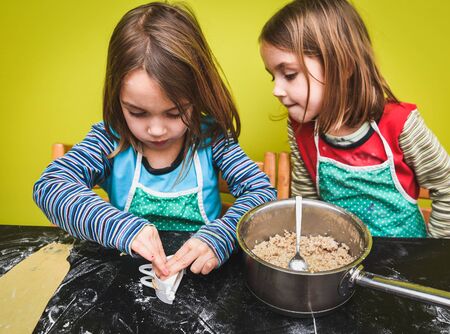 Little twin girls are making home made pastry dumplings tortellini or ravioli.の写真素材
