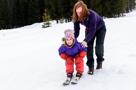 Professional ski instructor is teaching a child to ski on a sunny day on  a mountain slope resort with sun and snow. Family and children active vacation.の写真素材