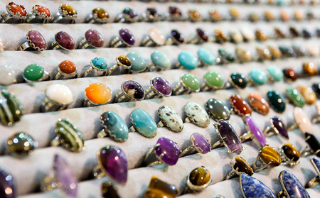 Display with different design of handmade rings with stones beads. Different variety of Gemstone rings on a display stand in a jewelry shopの写真素材