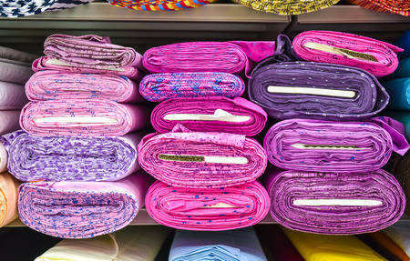 Rolls of fabric and textiles in a factory shop. Multi different colors and patterns on the market.
