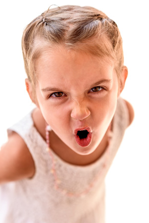 Portrait of a little girl with braids screaming. Child with braided hair is looking at the camera, yelling.の写真素材