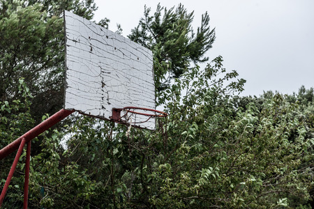 Old abandoned school sports court or schoolyard for different activities. Ruins of a sport venue abandoned long time ago with soccer, handball or football goals, basketball hoops and boards and destroyed concrete plates.の写真素材
