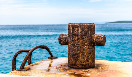 Old rusty steel mooring bollard pole on a pier. The best way for boat or ship mooring in harbor. Croatia, Silba.の写真素材