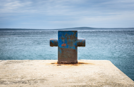 Old rusty steel mooring bollard pole on a pier. The best way for boat or ship mooring in harbor. Croatia, Silba.の写真素材