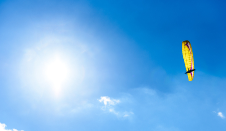 Paraglider flying against the blue sky with white clouds. Parachute on  a clear blue sunny day with sun and clouds.の写真素材
