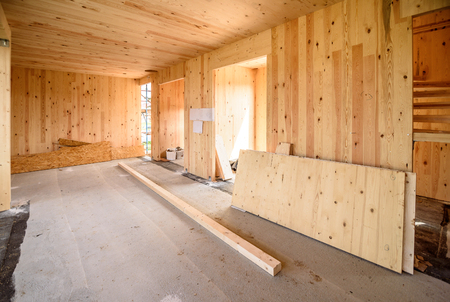 Building energy efficient passive wooden house. Construction site and interior of a wooden panel house with scaffolds ready for wall insulation and different installations.の写真素材
