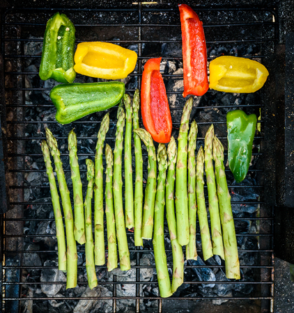 Asparagus and bell peppers on a barbecue bbq charcoal grill. Delicious vegan barbecue outdoors picnic meal. Grilling vegetables for vegetarians or vegans.の写真素材