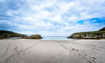 Atlantic sandy beach in Galicia Spain. Tropical sandy beach with dramatic clouds and atlantic ocean and tracks in the sand.の写真素材