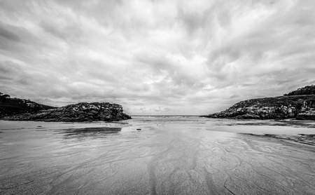 Atlantic sandy beach in Galicia Spain. Tropical sandy beach with dramatic clouds and atlantic ocean and tracks in the sand.の写真素材