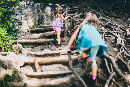 Children - twin girls are hiking in the mountains. Active family, parents and children mountaineering in the nature.の写真素材