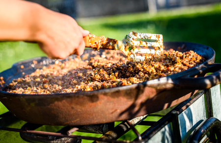 Cooking and making traditional Spanish Paella in iron cast pan. Preparing big paella outdoors on front yard party or business event. Professional catering buffet food.の写真素材