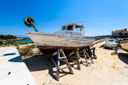 Repair and restoration of old wooden fishing ship or boat. Old weathered fishing boat mounted on...