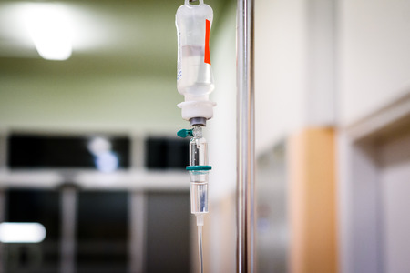 Intravenous therapy iv infusion set and bottle on a pole. Liquid saline is slowly dripping drops of drugs, medicine or antibiotic therapy and surgery recovery in a hospital or clinic.の写真素材