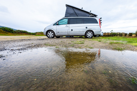 Campervan or motorhome camping on rainy day with rain puddles. Family vacation road trip with camper van, motor home or RV in with bad weather. Holiday travelling to Atlantic ocean - Spain or Portugalの写真素材