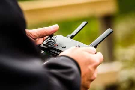 Hand holding drone quadcopter UAV remote control console controls. Professional  drone operator is...