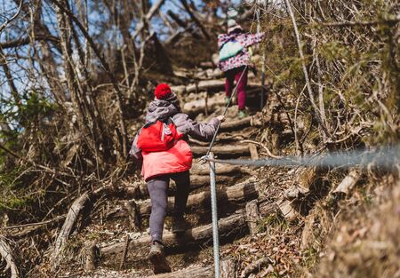 Children hiking in the mountains or woods on family trip. Active family, parents and children mountaineering in the nature. Kids are walking in woods trail road in cold winter time.の写真素材