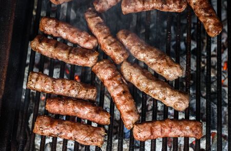 Grilling Meat on barbecue grill with hot coal. Preparing, cooking cevapcici, kebabs, country sausage...