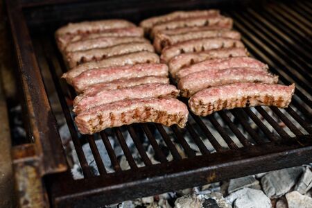 Grilling Meat on barbecue grill with hot coal. Preparing, cooking cevapcici, kebabs, country sausage...